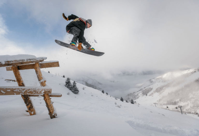 Photographie d'un snowboarder sautant au dessus d'une table